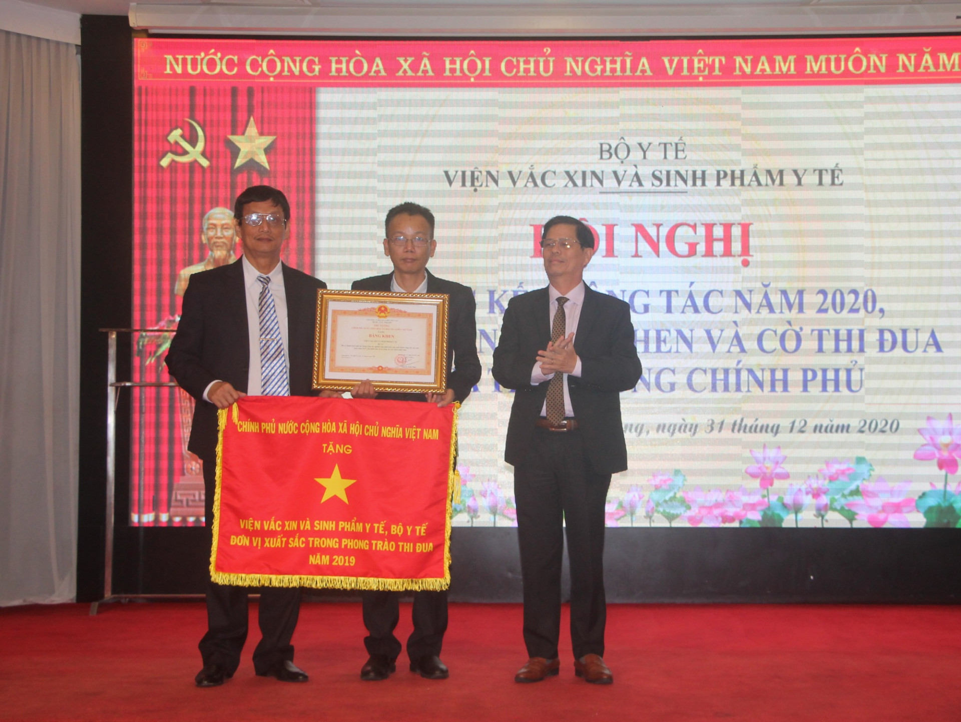 Ông Nguyễn Tấn Tuân trao cờ thi đua của Chính phủ cho lãnh đạo Viện Vắc xin và Sinh phẩm Y tế