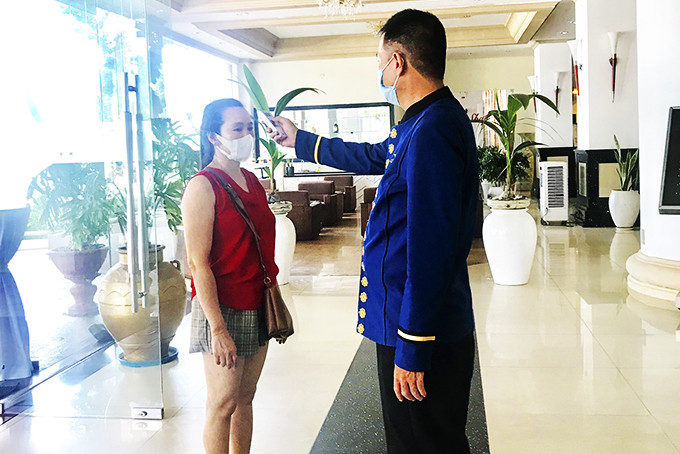 Nhân viên khách sạn Yasaka-Saigon-Nhatrang đo thân nhiệt cho khách. 