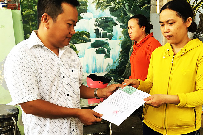 Công chức tư pháp - hộ tịch xã Vĩnh Thạnh (bìa trái) trao trích lục khai tử tại gia đình có công dân mất. 