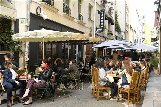 Người dân thưởng thức đồ uống bên ngoài một nhà hàng ở Paris, Pháp, ngày 19/5/2021. Ảnh: AFP/TTXVN