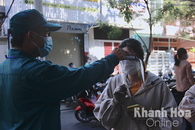 Người dân đo thân nhiệt trước khi vào điểm tiêm vacxin tại Kho Bạc nhà nước tỉnh Khánh Hòa. (Ảnh: Minh Trúc)