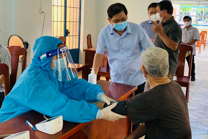 Chủ tịch UBND tỉnh Nguyễn Tấn Tuân thăm hỏi người dân tại điểm tiêm vắc xin ở Trường Tiểu học Cam Đức, huyện Cam Lâm.