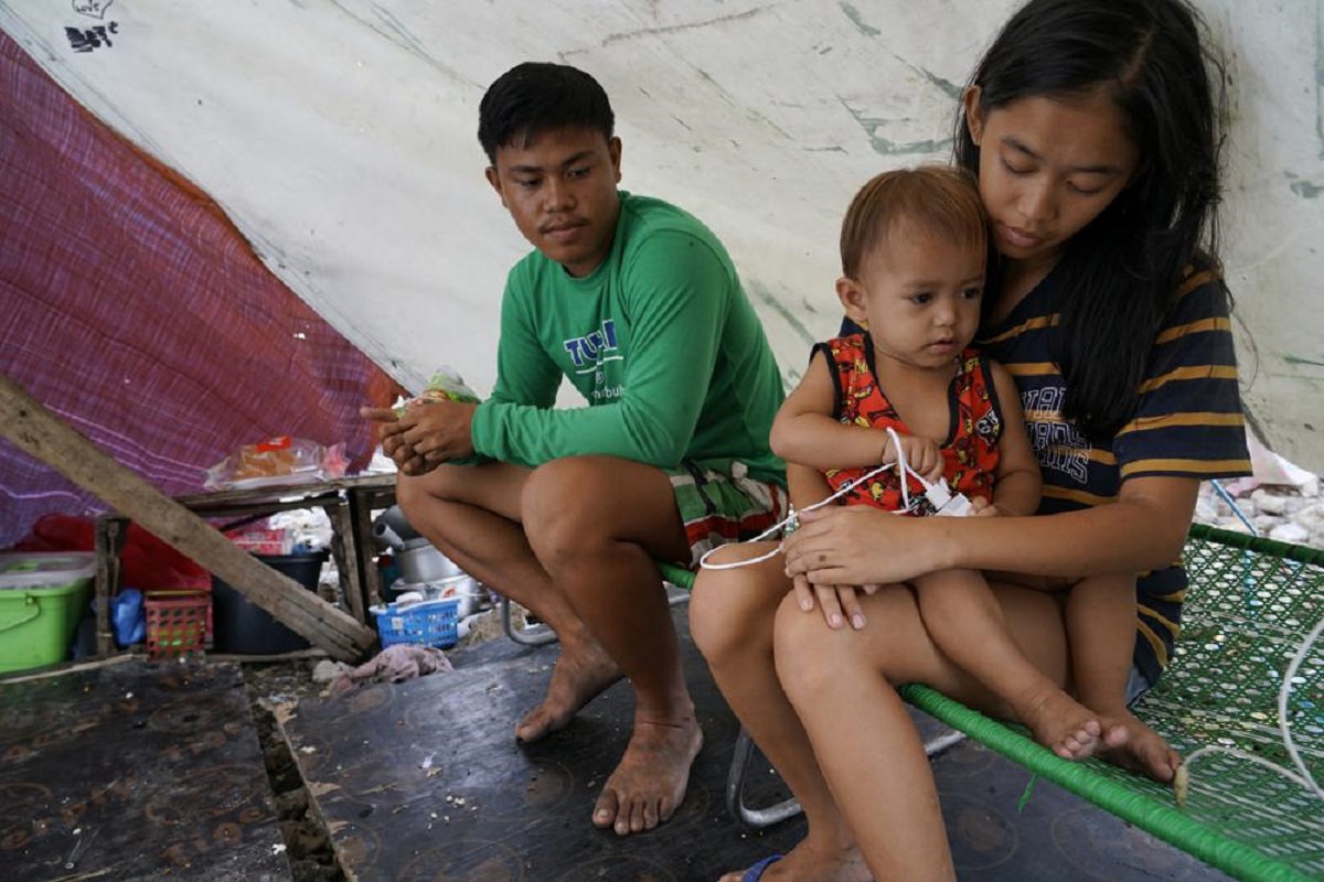 Leahmer Singson bế con trai bên cạnh chồng Jay Rabina trong căn lều tạm ở Mambaling, Cebu, miền trung Philippines trong ngày cuối cùng của năm 2021. Một đám cháy bùng phát vào cuối tháng 11 buộc người dân địa phương phải tạm trú ở những căn lều tạm. Sau đó, nơi này cũng đã bị tàn phá nặng nề do siêu bão Rai. Khi được hỏi cô mong muốn điều gì cho năm mới, Singson chỉ có 1 điều ước giản đơn:  "Tôi hy vọng chúng tôi sẽ không bị ốm ". (Ảnh: AP) 