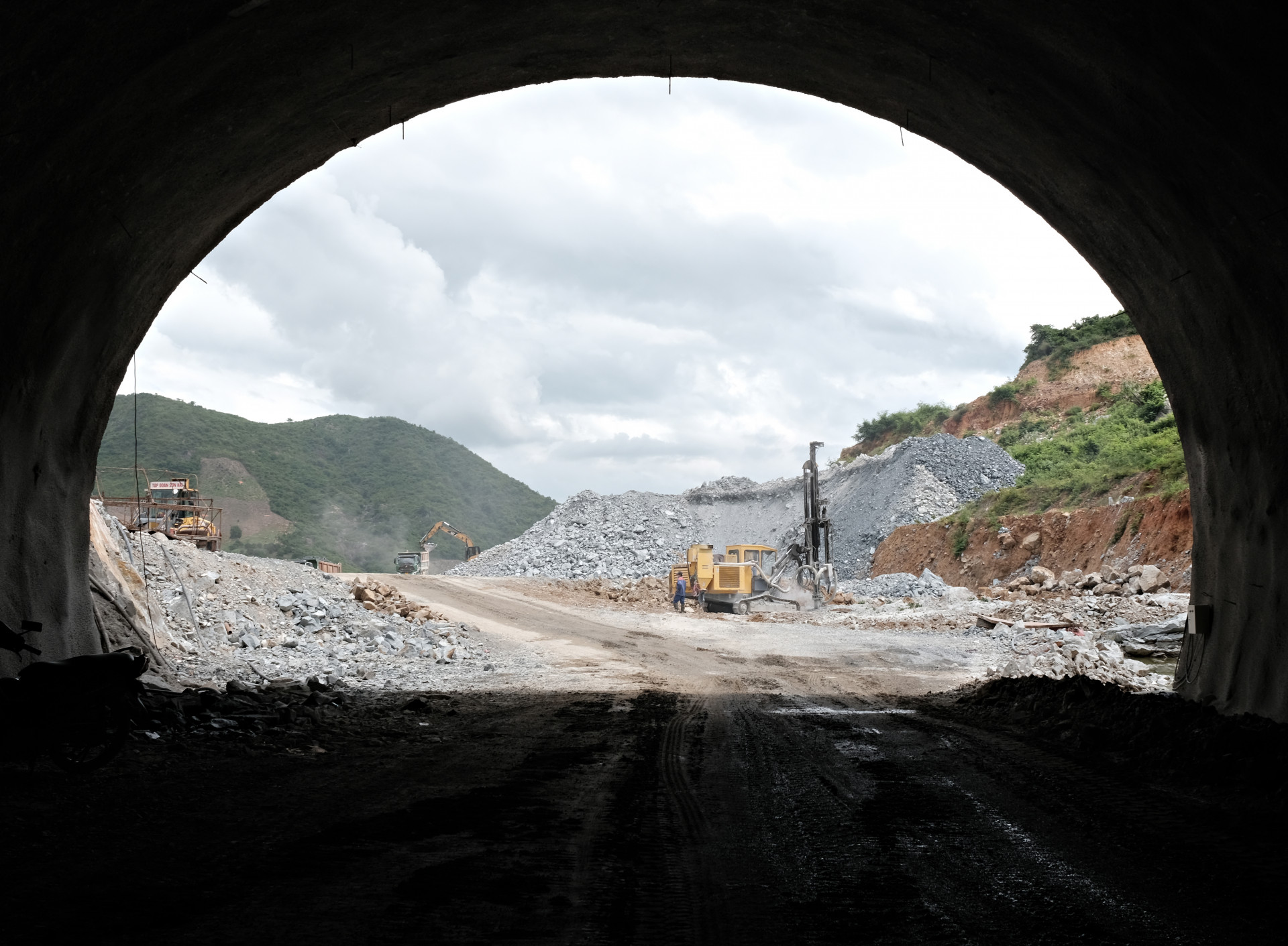 Công nhân và máy móc phải hoạt động liên tục để đục đá cho việc thi công đường dẫn vào hầm Dốc Sạn.