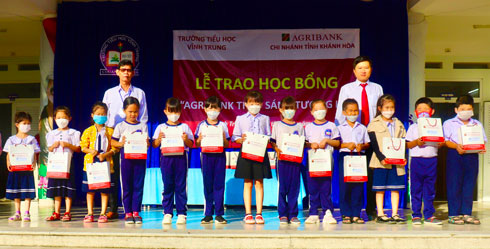 Đại diện Agribank Chi nhánh tỉnh Khánh Hòa và Hiệu trưởng Trường Tiểu học Vĩnh Trung trao học bổng cho các em học sinh.