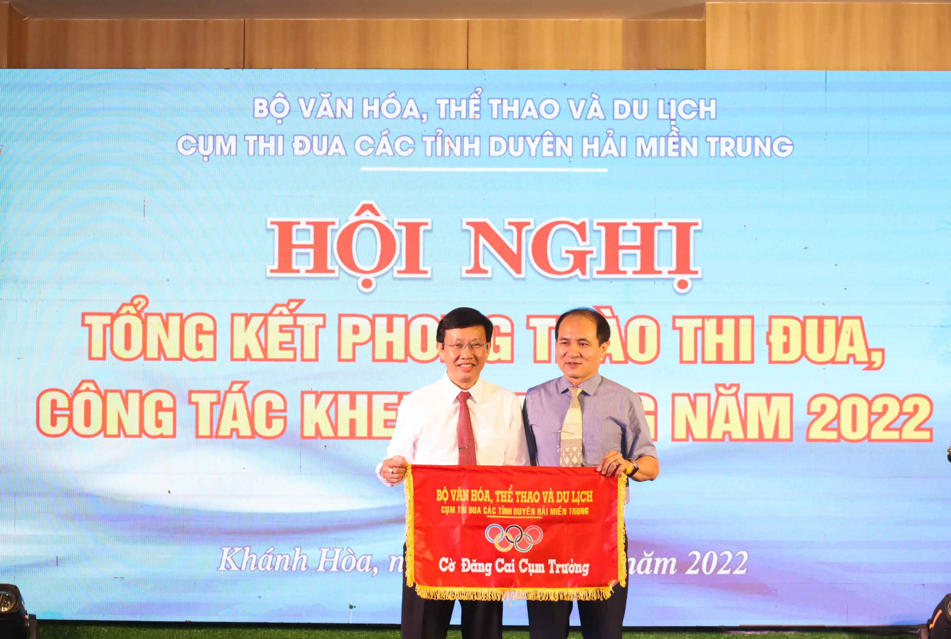 Lãnh đạo Sở Văn hóa và Thể thao tỉnh Khánh Hòa (phải) trao cờ cụm trưởng cho lãnh đạo Sở Văn hóa, Thể thao và Du lịch tỉnh Ninh Thuận. 
