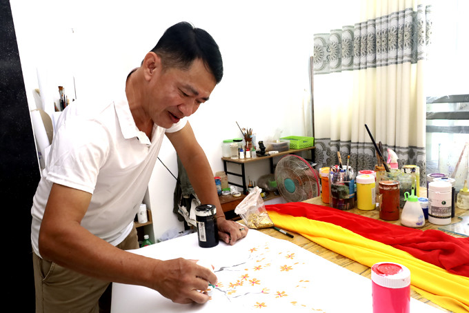 Ông Tạ Ngọc Thọ đang phác thảo một bức tranh trước khi vẽ lên áo dài cho khách.
