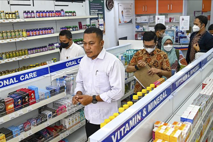 Cảnh sát kiểm tra thuốc siro ho tại một hiệu thuốc ở Banda Aceh, Indonesia, ngày 24/10/2022. Ảnh: AFP/TTXVN